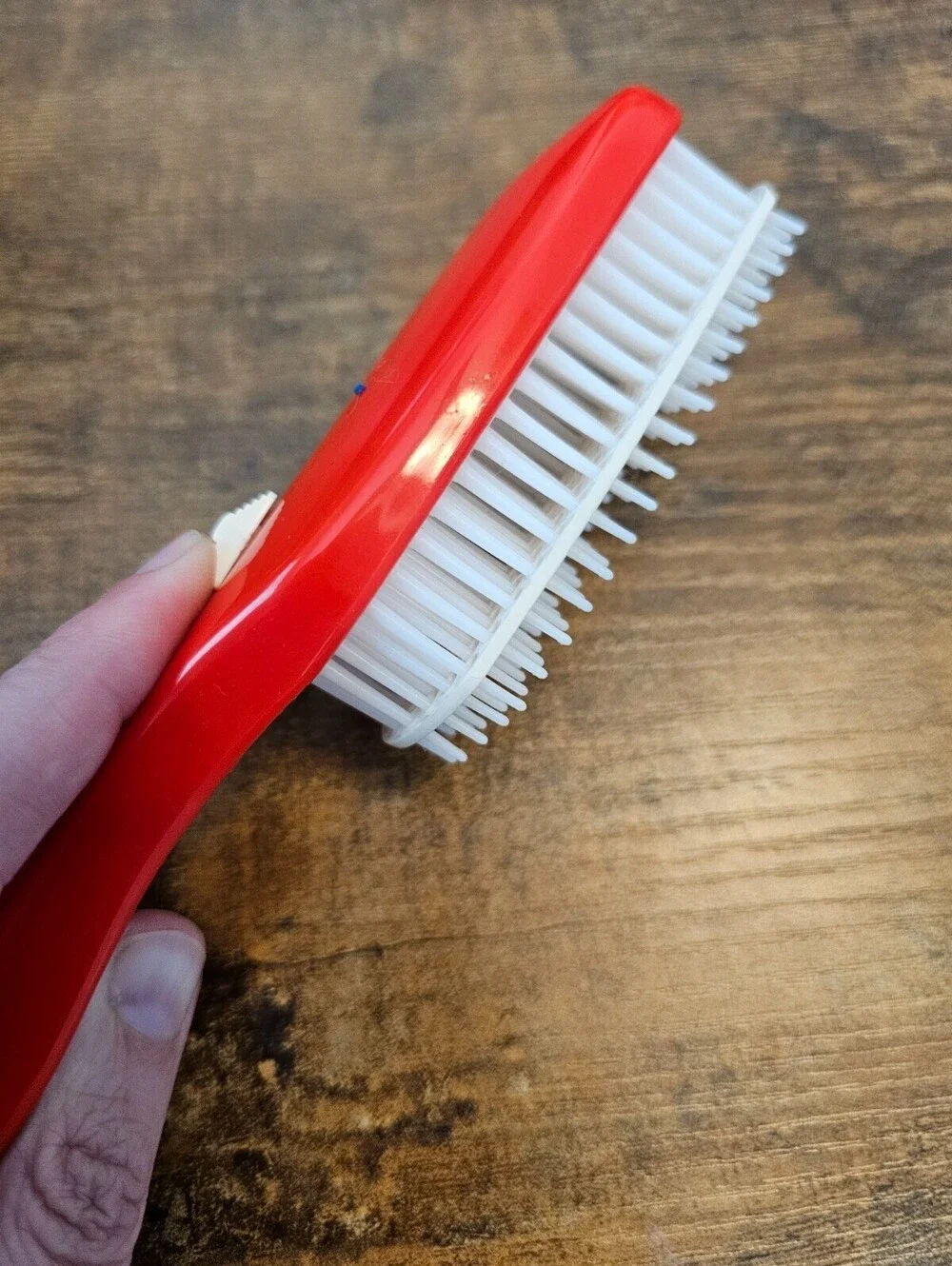 Vintage 1970s hair brush with a red handle and flexible white bristles